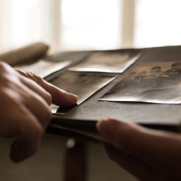 Hands holding and pointing at old photographs.