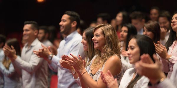 A diverse audience standing and applauding during an event.