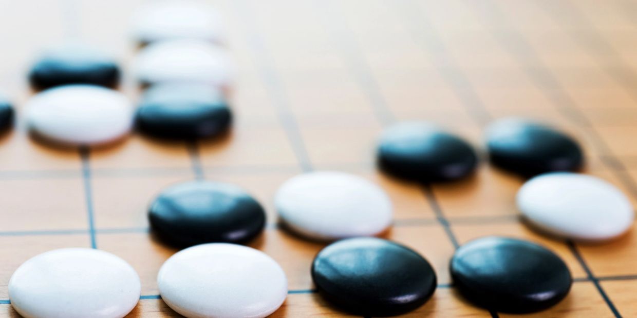Close-up of black and white Go game stones on a wooden board.