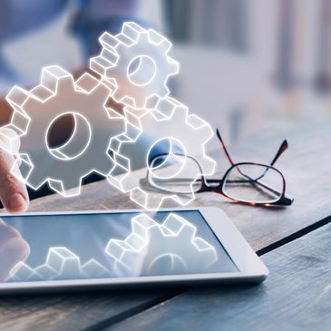 Hand interacting with tablet displaying digital gear icons.