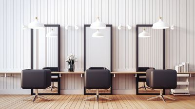 Modern salon interior with black chairs and large mirrors.
