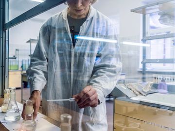 Scientist conducting an experiment in a laboratory with various glassware.
