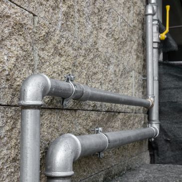 Metal pipes running horizontally along a textured stone wall.