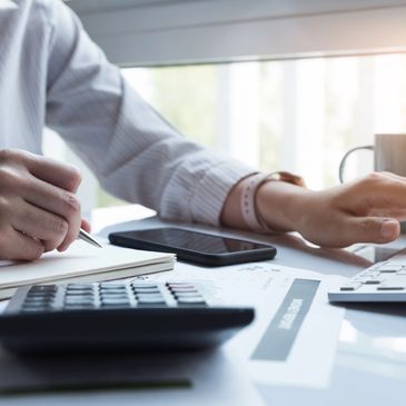 a woman working at a desk with a calculator and a pen