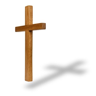 Wooden Christian cross casting a shadow on a white background.