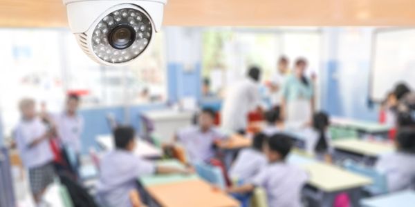 Security camera monitoring a busy classroom with children and teachers.