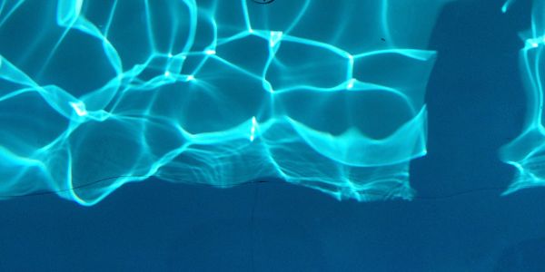 Sunlight reflections creating patterns on a blue water surface.