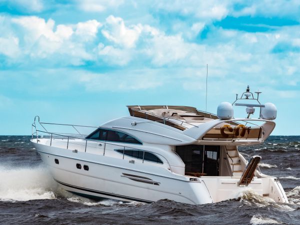 A white luxury yacht cruising on the ocean under a blue sky.