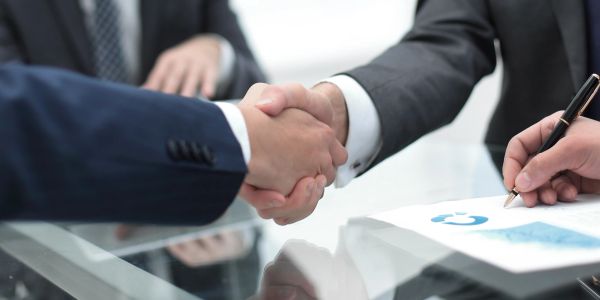 Business handshake over a desk with a contract.