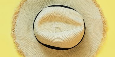 A straw hat with a black band on a yellow background.