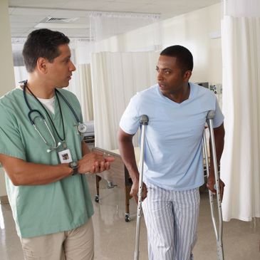 Doctor consulting a patient on crutches in a hospital.