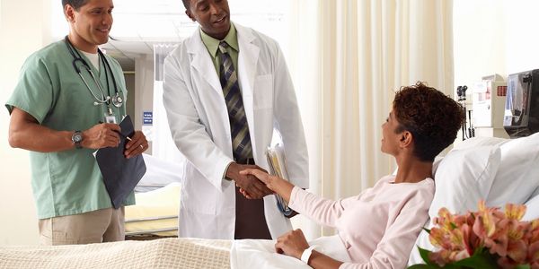 Doctor shaking hands with a female patient in a hospital room.