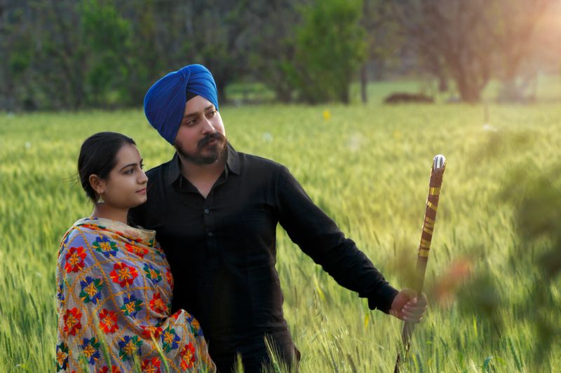 Sikh couple in a Wheat field with bhangra stick