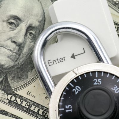 Combination lock on a keyboard key with dollar bills in the background.