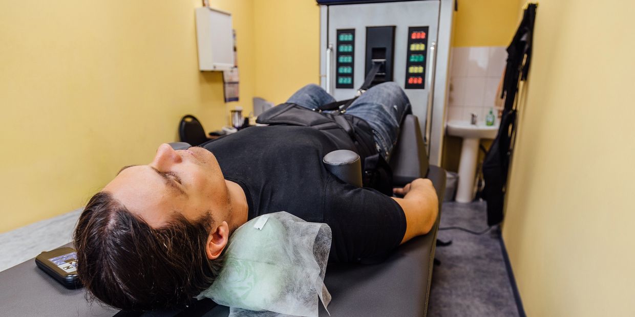 Man lying down on a therapy table in a small room.