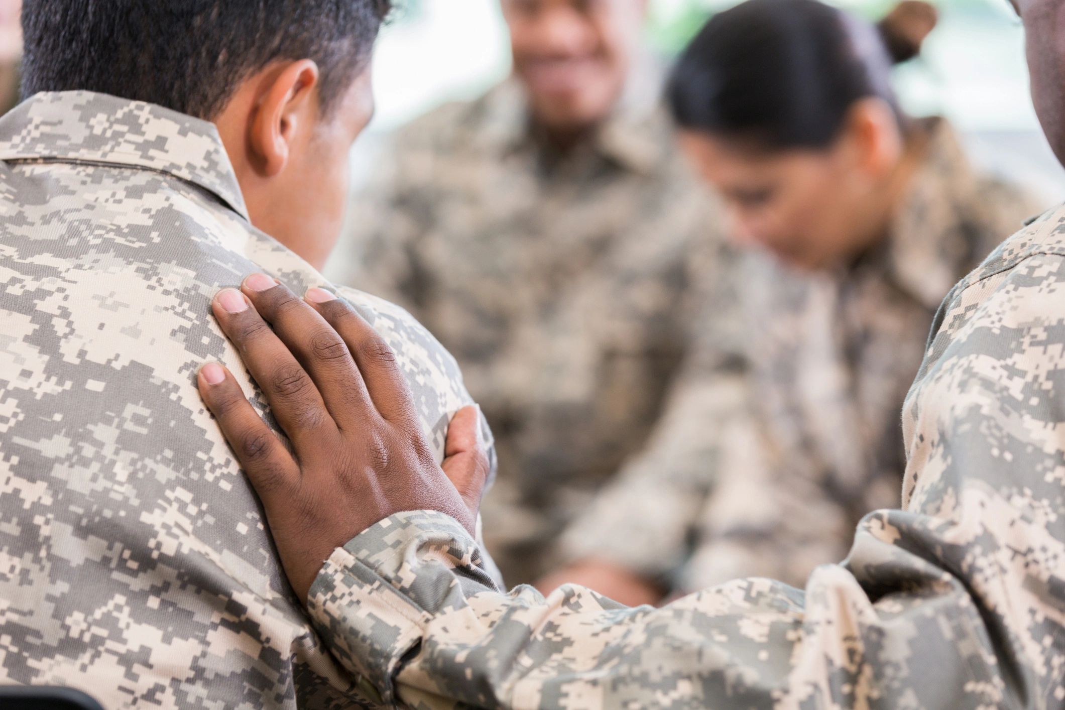 A soldier comforting another with a supportive hand on the shoulder.