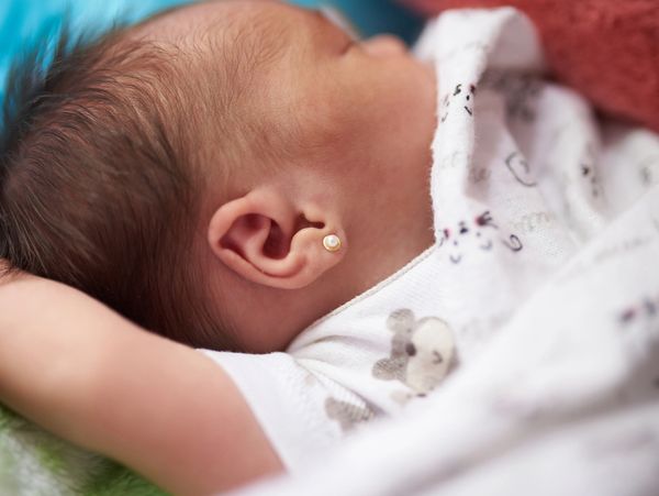 Close-up of a sleeping baby with a small pearl earring.