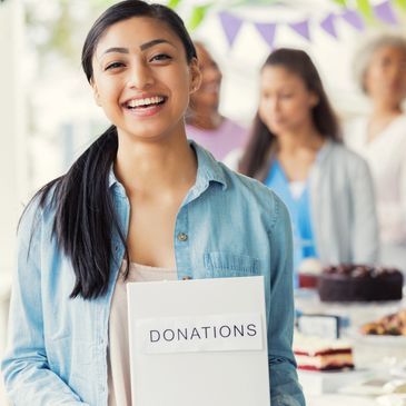 Smiling woman holding a donations box at a community event.