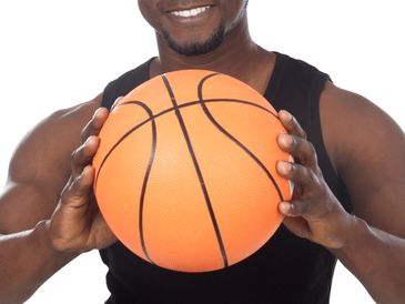 Smiling man holding a basketball in front of him.