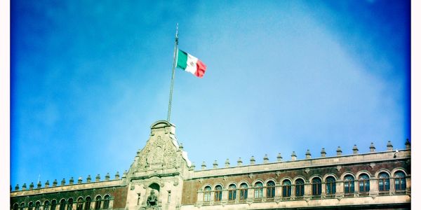 Historic building with Mexican flag flying above.