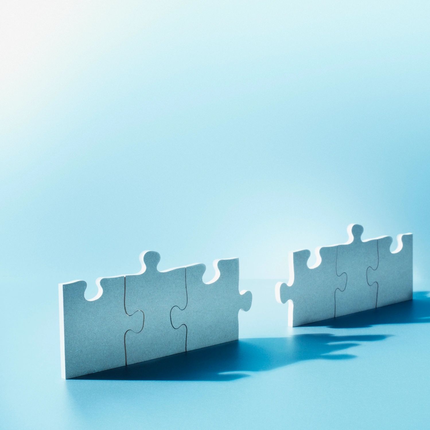 Two separated puzzle pieces standing upright on a blue surface.