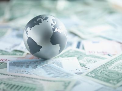 A globe resting on various international currencies.