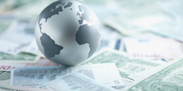 A metallic globe on scattered international currencies.
