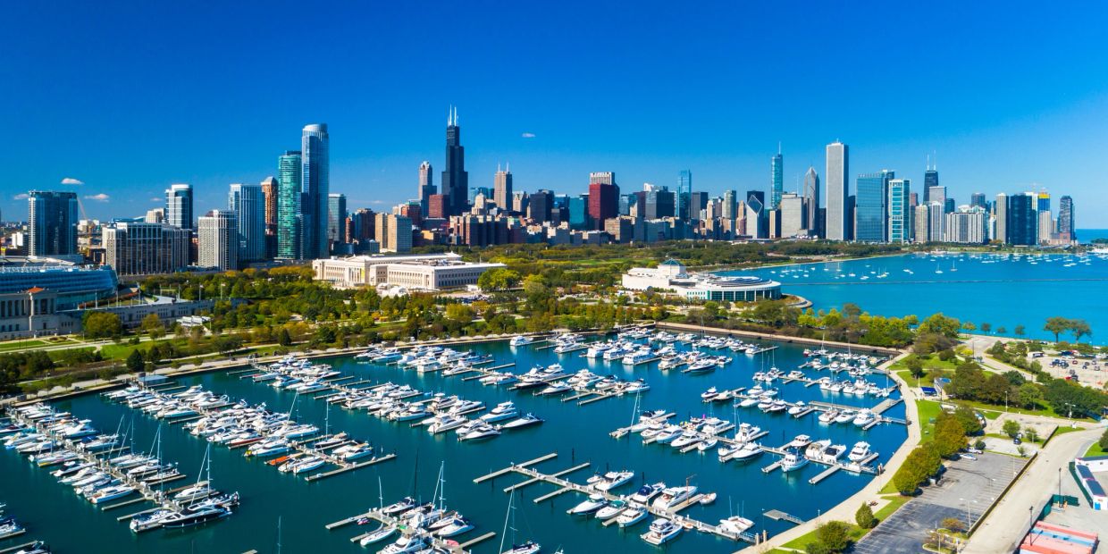 A vibrant marina filled with boats against a city's skyline under a clear blue sky.
