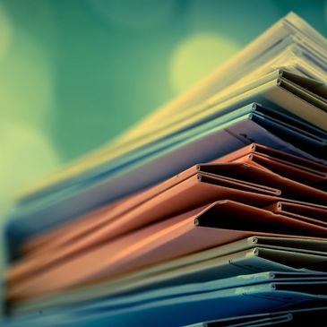 Stack of colorful folded newspapers with a soft green background.