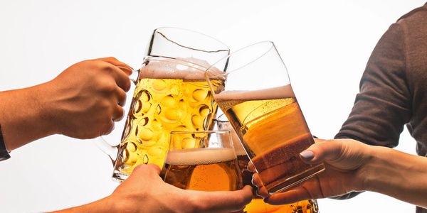 Four people clinking glasses of beer in a celebratory toast.