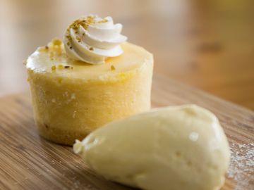 A small cheesecake topped with whipped cream and a scoop of ice cream.