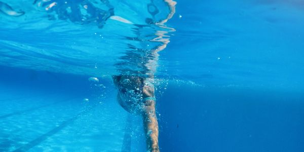 A swimmer stretching their arm underwater in a pool.