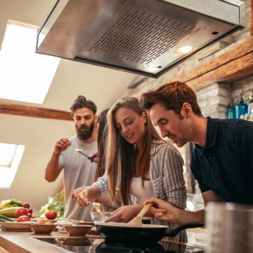 Three friends cooking together in a cozy kitchen.