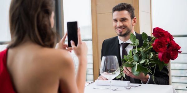 Man giving a bouquet of roses to a woman at a restaurant.