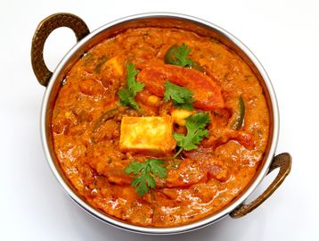 Paneer curry garnished with cilantro in a traditional serving bowl.