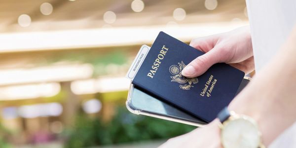 Hand holding a U.S. passport and a smartphone at an airport.