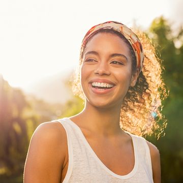 Smiling woman outdoors with sunlight.
