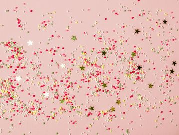 Colorful confetti scattered on a pink background.