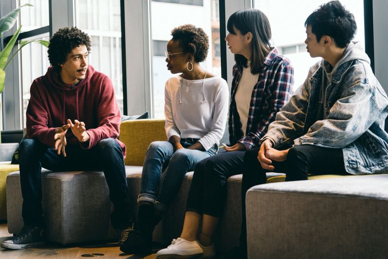 young men and women are talking in a meeting room