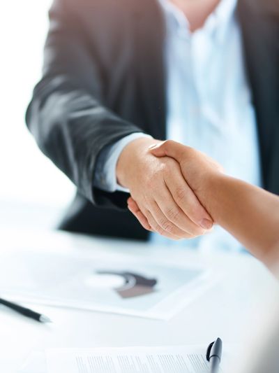 Two people shaking hands in a business setting.