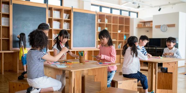Children engaged in arts and crafts at wooden tables.