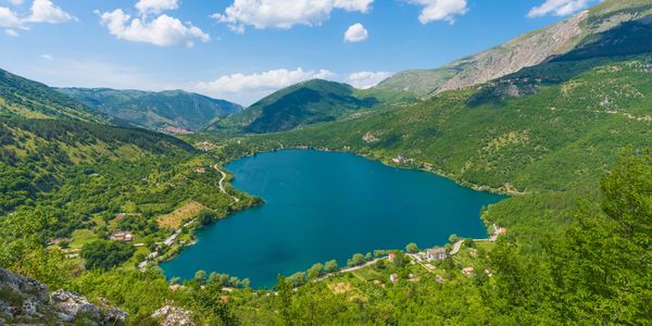 Scenic mountain lake surrounded by lush greenery under a blue sky.