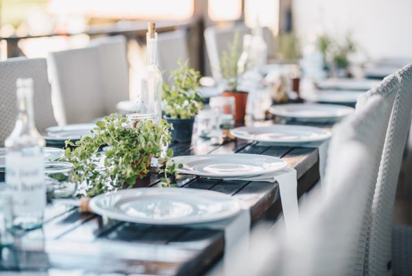 Elegant outdoor dining table set with white plates and greenery.