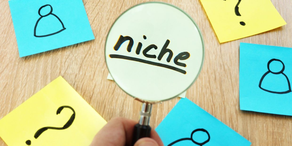 Magnifying glass highlighting the word 'niche' among sticky notes with question marks and person icons.