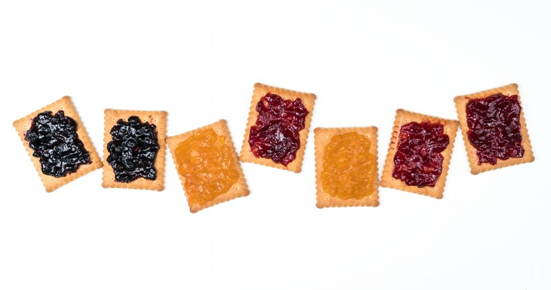 Some dry biscuits with jam on a white surface