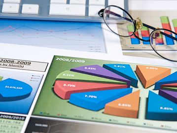 Pie charts and glasses on financial documents.