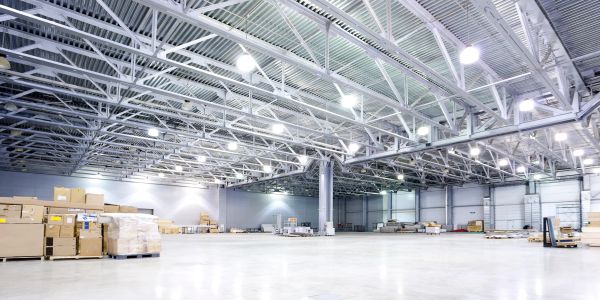 Large, well-lit industrial warehouse with metal beams and stacked boxes.
