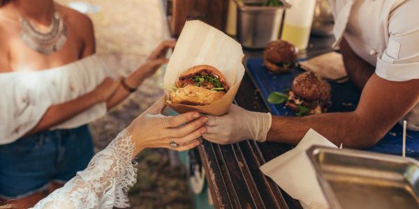 Person receiving a burger at a food stall.
