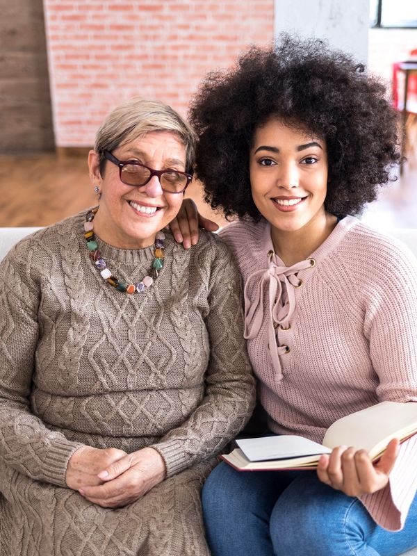Two women sitting on a couch, smiling.