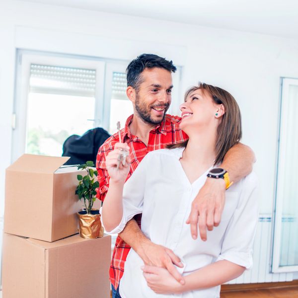 Happy couple holding keys inside their new home with moving boxes.